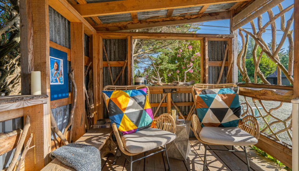 photo of a b.side motel and rv park outdoor seating area with rattan chairs that have white cushions and colorful orange and blue and white accent pillows