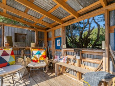 photo of a b.side motel and rv park outdoor seating area with rattan chairs that have white cushions and colorful orange and blue and white accent pillows